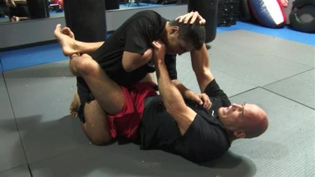 Hoe vraagt ​​een driehoek stikken van open bewaker in mixed martial arts. Begin met het leggen op je rug liggen met je benen uit elkaar.